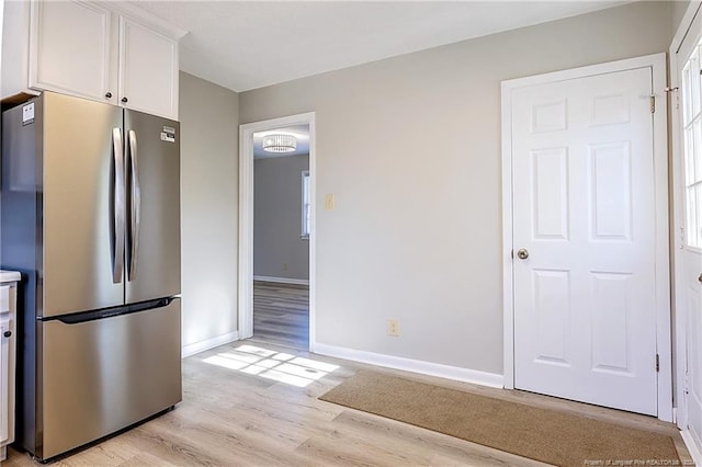 kitchen featuring stainless steel fridge, white cabinets, and light wood-type flooring