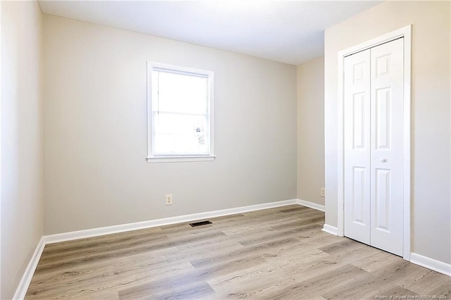 unfurnished bedroom with a closet and light hardwood / wood-style flooring