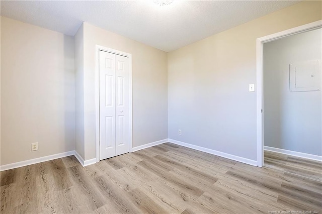 unfurnished bedroom featuring light hardwood / wood-style floors, a textured ceiling, and a closet