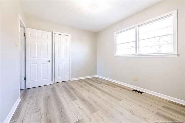 unfurnished bedroom with a closet, a textured ceiling, and light hardwood / wood-style flooring