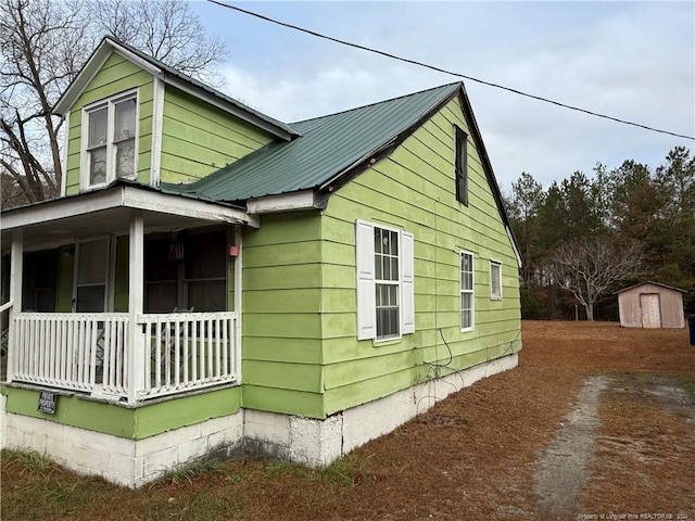 view of property exterior featuring a porch and a storage unit