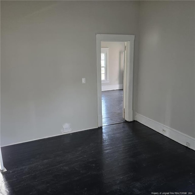 unfurnished room with dark wood-type flooring