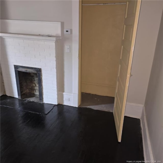 unfurnished living room with hardwood / wood-style floors and a brick fireplace