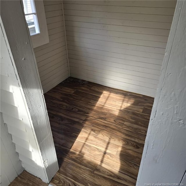 unfurnished room featuring dark hardwood / wood-style floors and wooden walls