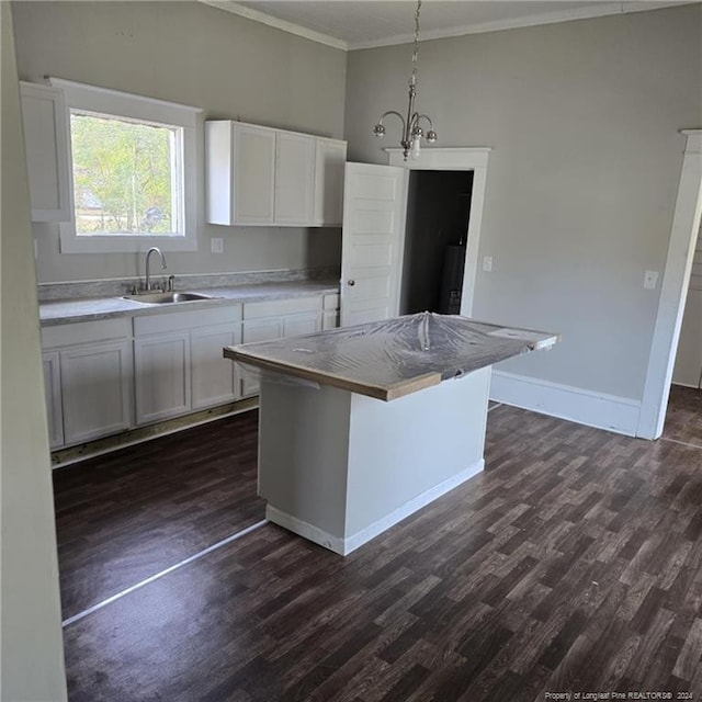 kitchen with white cabinets, a kitchen island, sink, and hanging light fixtures