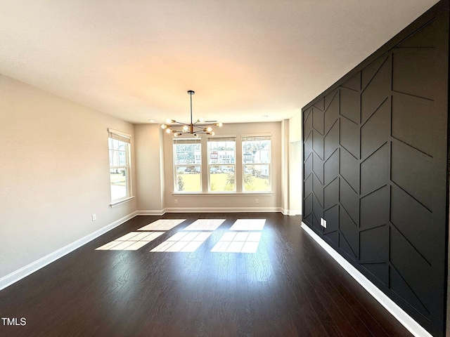 unfurnished room with a chandelier and dark hardwood / wood-style flooring