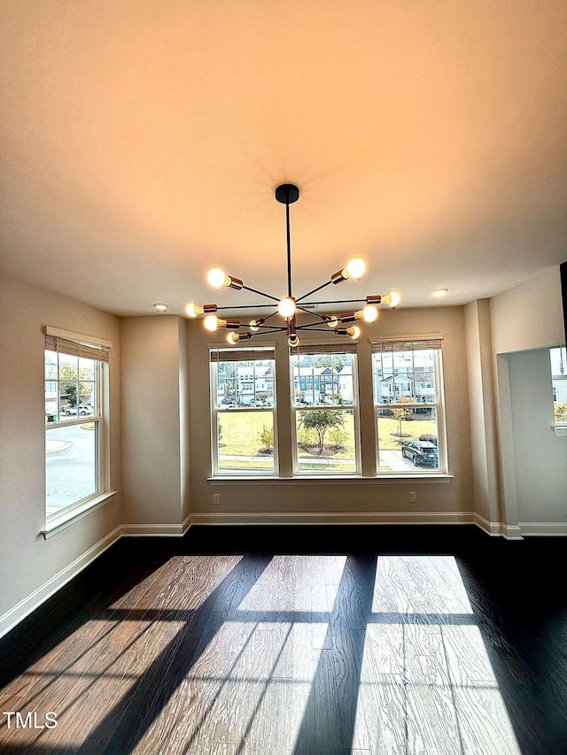 unfurnished room with plenty of natural light and a notable chandelier