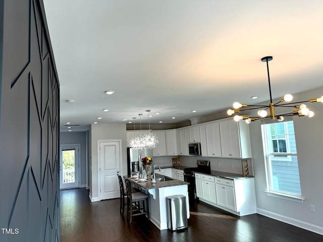 kitchen with white cabinetry, stainless steel appliances, a notable chandelier, pendant lighting, and a kitchen island with sink