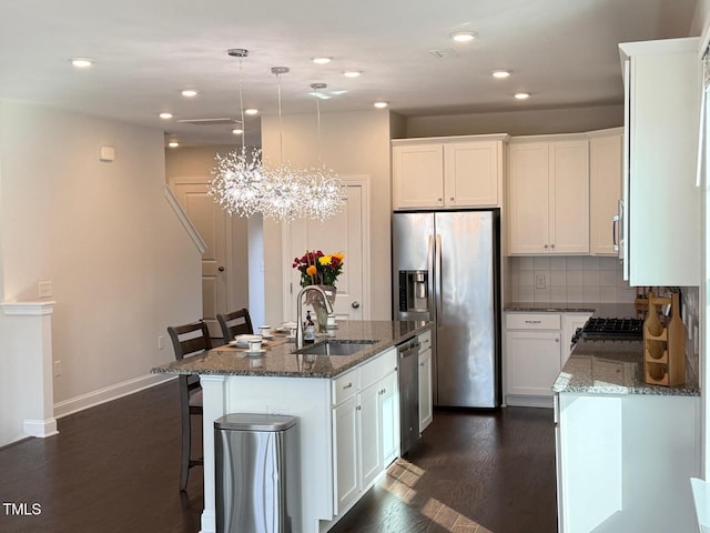 kitchen featuring white cabinetry, sink, pendant lighting, a center island with sink, and appliances with stainless steel finishes