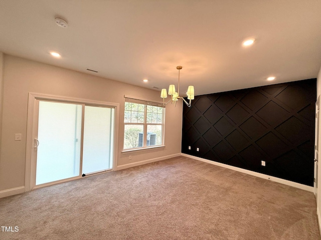 spare room with carpet and a chandelier