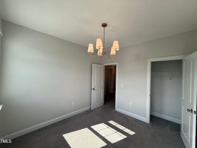 unfurnished bedroom featuring dark colored carpet, a notable chandelier, and a closet