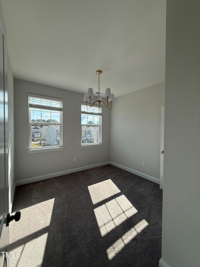 carpeted spare room featuring a notable chandelier