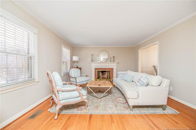 living room featuring hardwood / wood-style floors, ornamental molding, and a brick fireplace