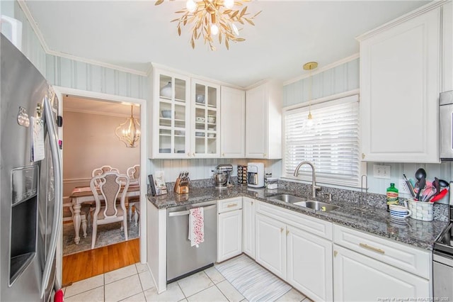 kitchen with white cabinets, stainless steel appliances, sink, and a notable chandelier