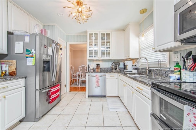 kitchen with white cabinetry, stainless steel appliances, sink, and dark stone countertops