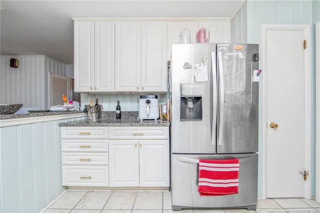 kitchen featuring white cabinetry, stainless steel fridge with ice dispenser, light tile patterned floors, and dark stone countertops