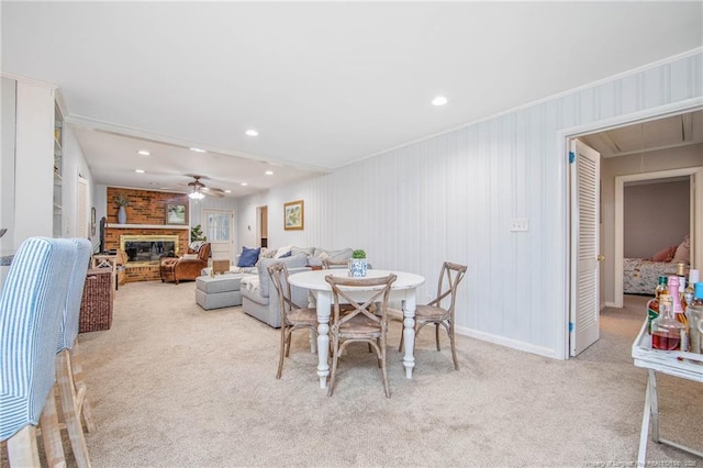 carpeted dining space with crown molding, ceiling fan, and a brick fireplace