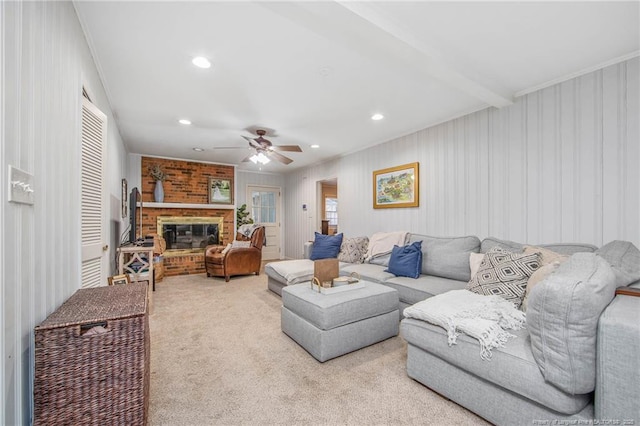 carpeted living room with a brick fireplace, beam ceiling, ornamental molding, and ceiling fan