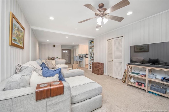 living room with light carpet, crown molding, and ceiling fan