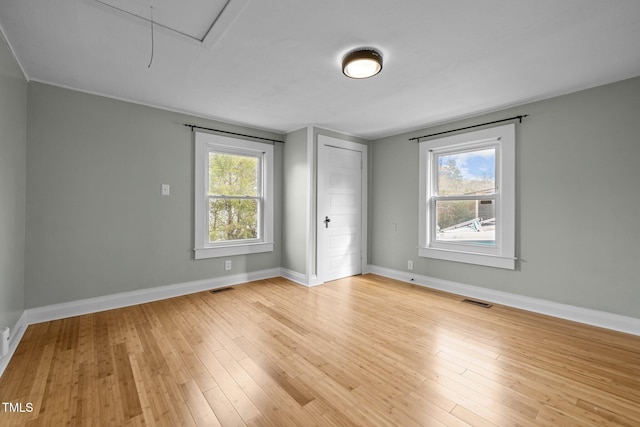 empty room with light hardwood / wood-style flooring and plenty of natural light