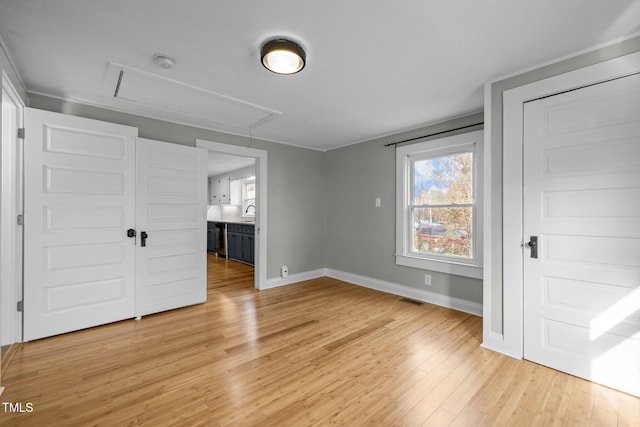 unfurnished bedroom featuring ensuite bathroom, light hardwood / wood-style flooring, and sink