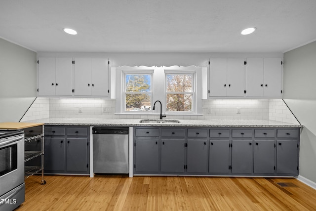 kitchen featuring decorative backsplash, appliances with stainless steel finishes, sink, light hardwood / wood-style flooring, and gray cabinets