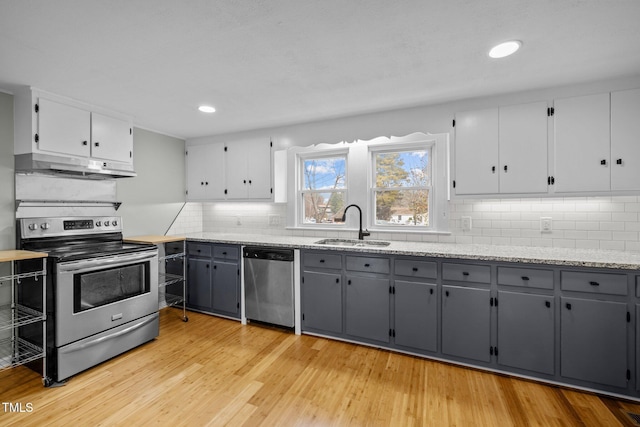 kitchen with sink, stainless steel appliances, gray cabinets, decorative backsplash, and light wood-type flooring