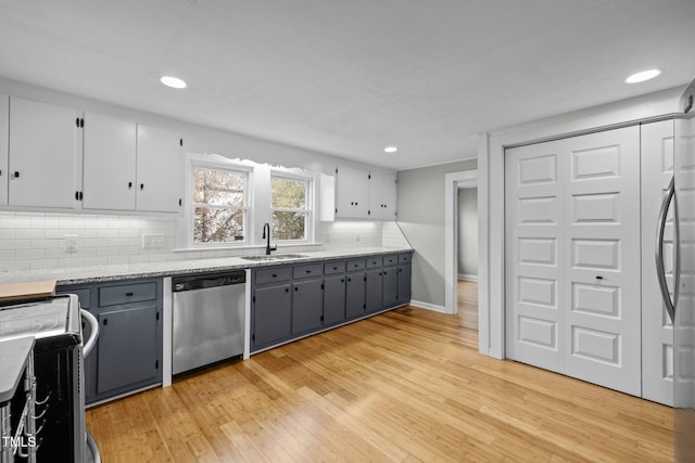 kitchen with decorative backsplash, stainless steel dishwasher, gray cabinetry, sink, and light hardwood / wood-style floors