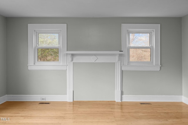 unfurnished living room with a healthy amount of sunlight and wood-type flooring