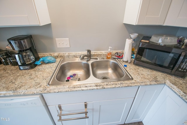 kitchen featuring dishwasher, sink, and white cabinets