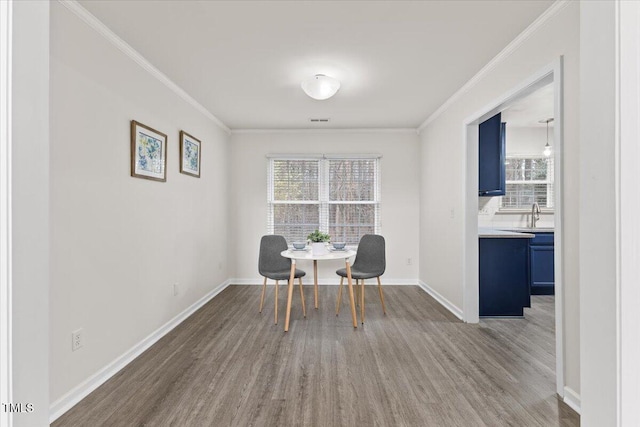 dining room with a wealth of natural light, crown molding, and wood finished floors