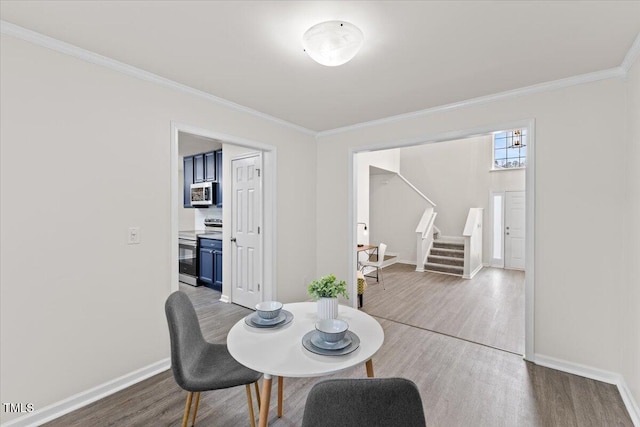 dining room with crown molding, stairway, baseboards, and wood finished floors