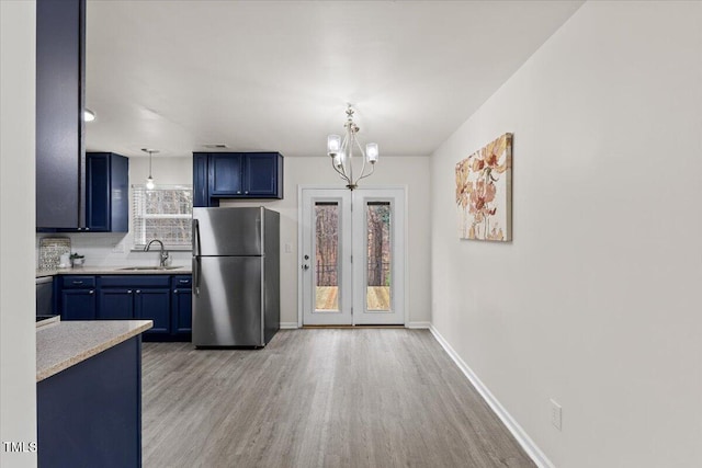 kitchen with blue cabinets, light countertops, a sink, and freestanding refrigerator