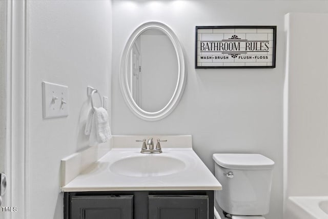 bathroom featuring a tub, vanity, and toilet