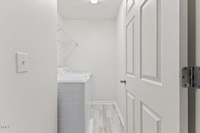 washroom with washer and dryer, laundry area, baseboards, and wood finished floors