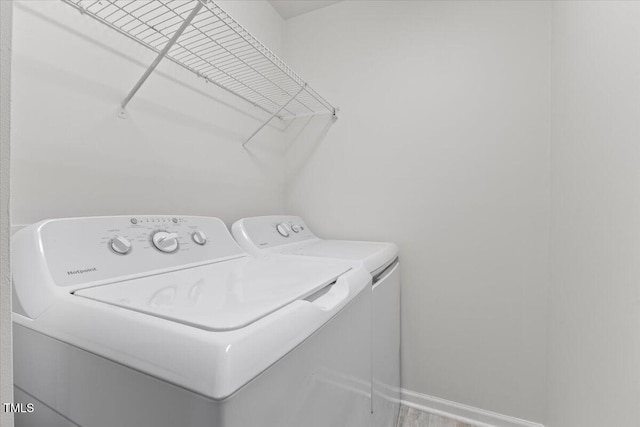 clothes washing area with laundry area, washer and clothes dryer, and baseboards