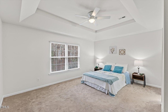 carpeted bedroom with a raised ceiling, visible vents, ceiling fan, and baseboards