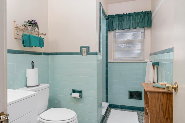 bathroom featuring tile patterned floors, vanity, toilet, and tile walls