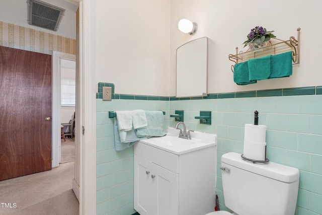 bathroom featuring vanity, tile walls, and toilet