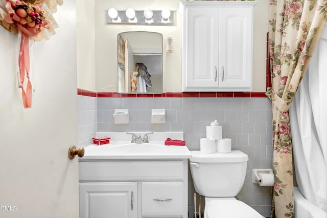 full bathroom featuring vanity, shower / bathtub combination with curtain, toilet, and tile walls