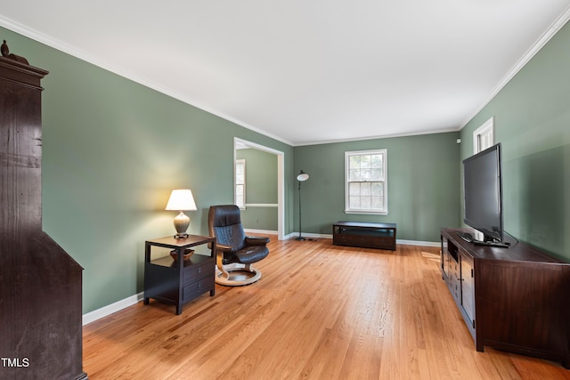 living area with ornamental molding, light wood finished floors, and baseboards