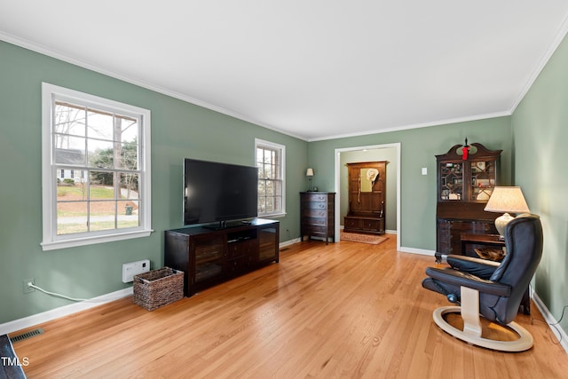 living area featuring visible vents, crown molding, baseboards, and wood finished floors