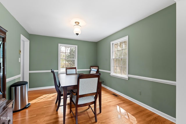 dining room with baseboards, light wood-style flooring, and a healthy amount of sunlight