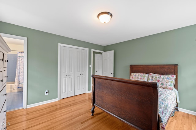 bedroom featuring a closet, connected bathroom, baseboards, and wood finished floors