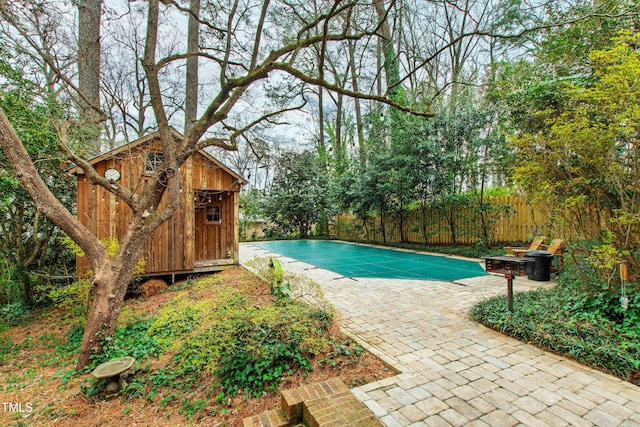 view of pool with a patio, fence, a fenced in pool, and an outdoor structure