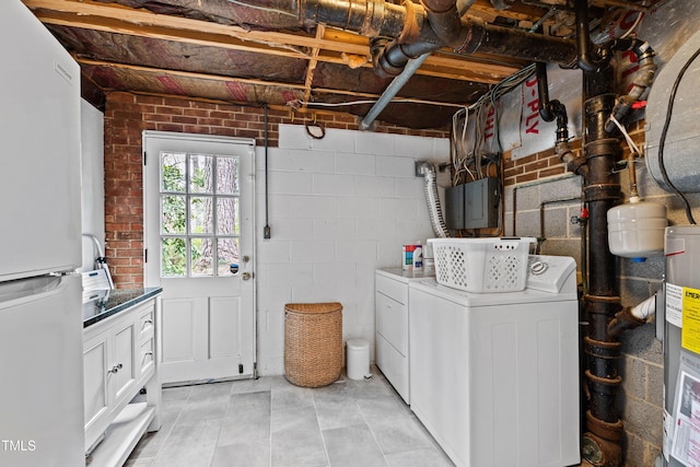 clothes washing area with washing machine and dryer, water heater, cabinet space, electric panel, and concrete block wall