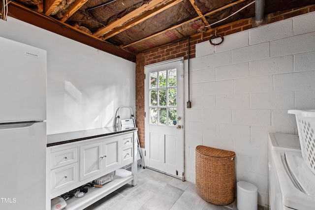 interior space with concrete block wall and independent washer and dryer