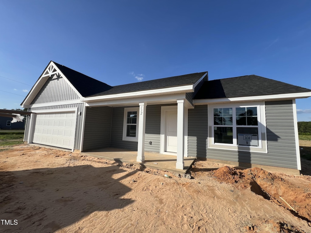view of front of property featuring a garage, dirt driveway, and a porch