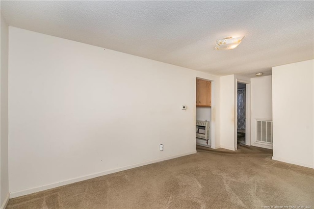 empty room with carpet flooring, heating unit, and a textured ceiling