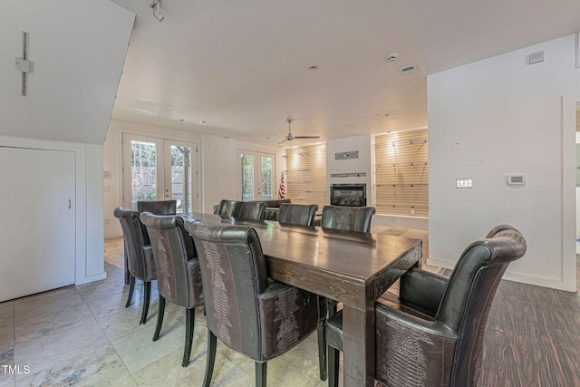 dining room with ceiling fan, a tile fireplace, and french doors